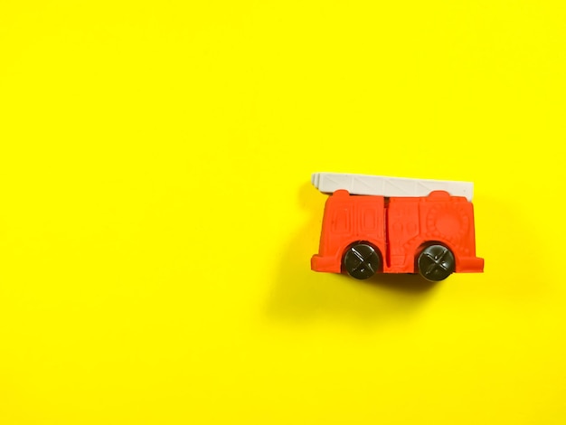 Brinquedo de caminhão de bombeiros vermelho em um fundo amarelo com espaço de cópia