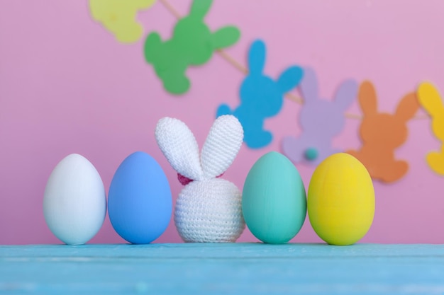 Brinquedo de coelho branco com ovos coloridos e decoração no espaço de cópia de fundo rosa da Páscoa