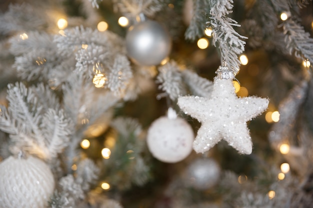 Brinquedo de Natal branco pendurado em um galho de abeto verde nevado