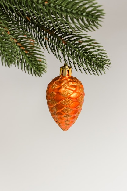 Brinquedo de Natal em forma de cone de abeto no galho verde. Conceito de decoração de árvore de natal