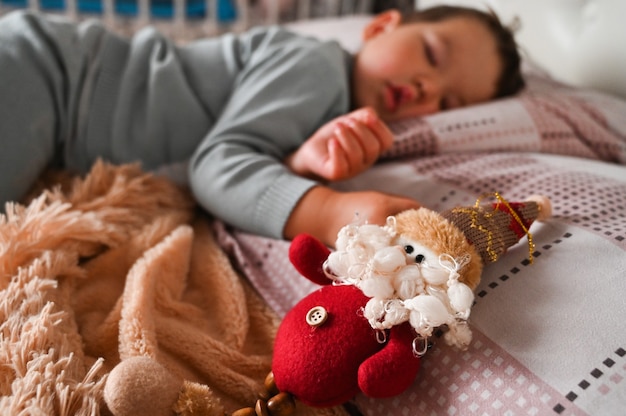 Brinquedo de Natal no fundo de um menino dormindo. Conceito de milagre de férias. Foto de alta qualidade