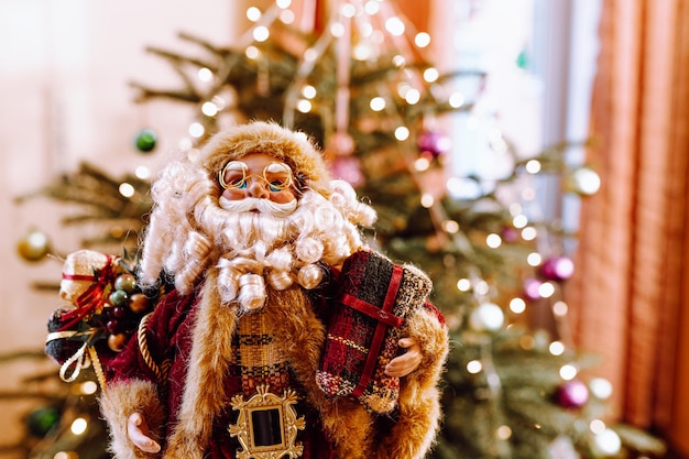 Brinquedo de Natal Papai Noel com presentes no fundo desfocado da árvore de Natal no interior de casa