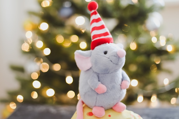 Brinquedo de ratinho e decorações de ano novo com luzes de bokeh de uma árvore de Natal