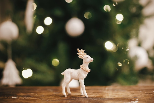 Brinquedo de rena elegante em madeira rústica contra árvore de natal em luzes copiar espaço feliz natal