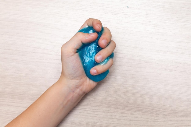 Brinquedo extensível de lodo azul para crianças nas mãos Um brinquedo elástico antiestresse para relaxamento Goma para as mãos Jogos engraçados Slime isolado Copie o espaço para o texto