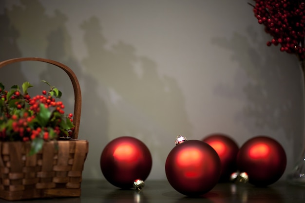 Foto brinquedo mate e brilhante para árvore de natal de cor vermelha perto das cestas de vime com frutas e galhos