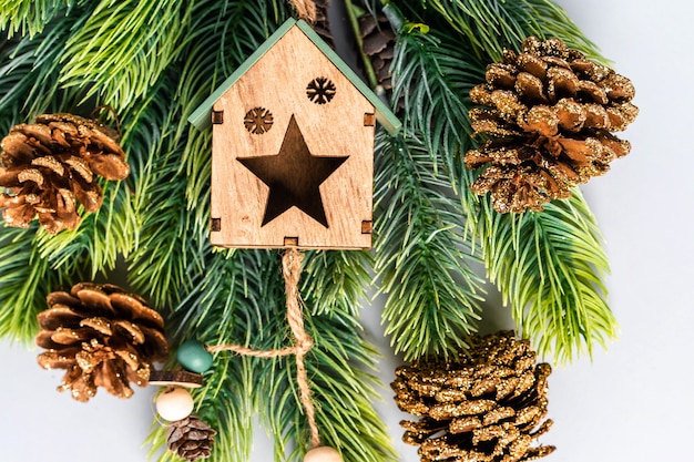 Brinquedo para árvore de natal na forma de uma casa de madeira em um galho de árvore