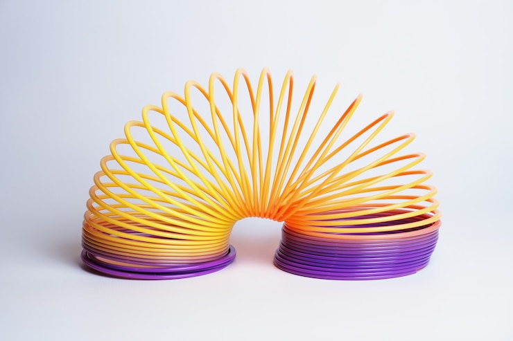 Brinquedo popular de plástico Slinky em um brinquedo de fundo branco na forma de uma mola longa e flexível