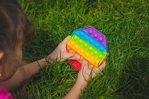 Brinquedo sensorial antistress colorido fidget push pop-lo nas mãos da criança. Foco seletivo. natureza.