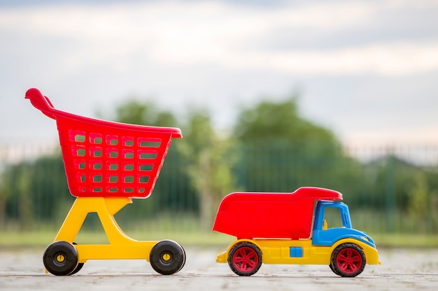 Brinquedos coloridos plásticos brilhantes para crianças ao ar livre num dia ensolarado de verão. caminhão de carro e carrinho de compras.