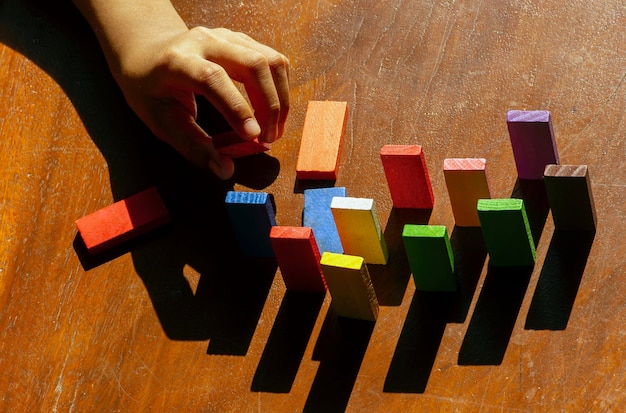 Foto brinquedos de madeira coloridos, brinquedos educativos de lógica para crianças com mão de criança de perto, ao sol da manhã