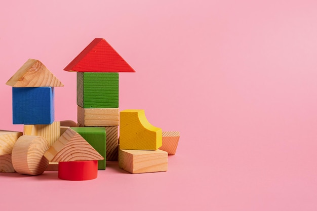 Foto brinquedos de madeira para crianças em um conceito de fundo rosa zero oeste pequenas casas o designer de desenvolver cubos de cor