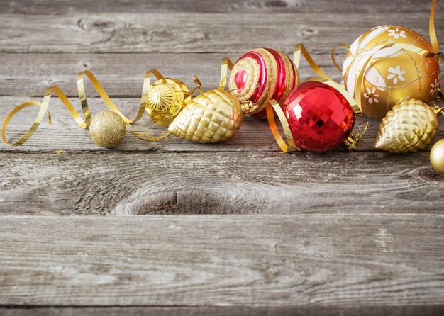 Brinquedos de Natal vermelhos e dourados em fundo de madeira velho