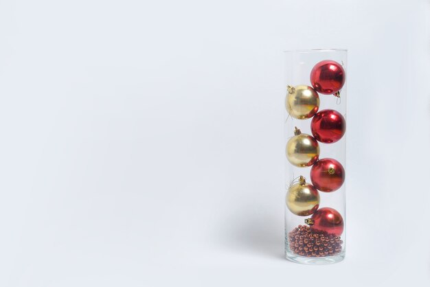 Brinquedos de natal vermelhos e dourados em um vaso em um fundo branco e isolado. banner de layout de ano novo. espaço para texto