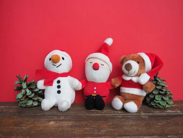 Brinquedos macios de natal costurados de pelúcia em um fundo vermelho cones pintados um pequeno boneco de neve sorridente urso pardo