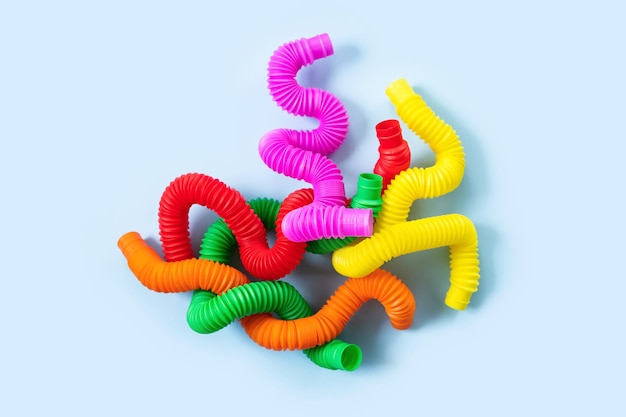 Brinquedos sensoriais coloridos anti-stress fidget push pop para crianças sobre fundo azul. vista superior, configuração plana. close-up de um jogo criativo com um popular cachimbo ondulado de plástico flexível e brilhante.