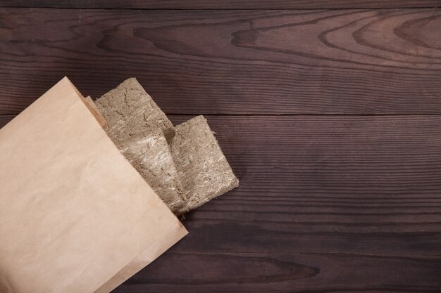 Las briquetas de halva de girasol se encuentran en una bolsa de papel artesanal sobre un fondo de madera. Concepto de desperdicio cero.