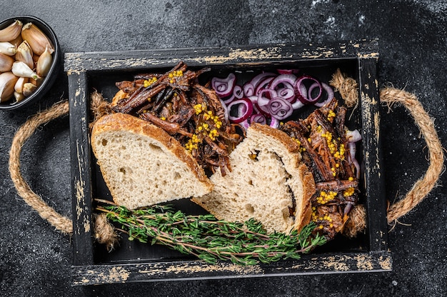 Brisket Sandwich mit geräuchertem Rindfleisch in einem Holztablett. Schwarzer Hintergrund. Ansicht von oben.