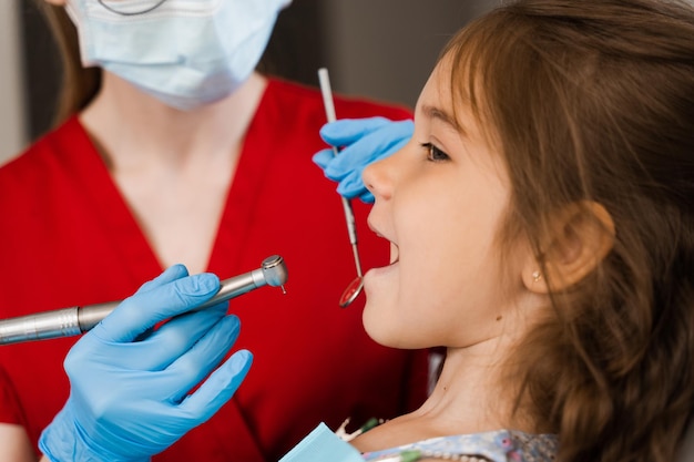 Broca odontológica closeup Dentista infantil perfurando os dentes de uma menina na clínica odontológica Tratamento dos dentes Enchimento dentário para paciente infantil