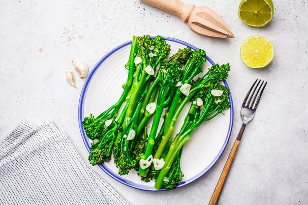 Broccolini fervido com alho em uma placa branca.