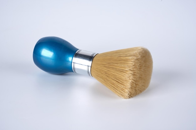 Una brocha de afeitar azul sobre un fondo blanco aislado.