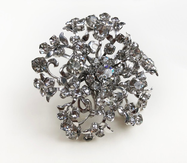 un broche hecho de plata y diamantes de plata se muestra con una flor en él