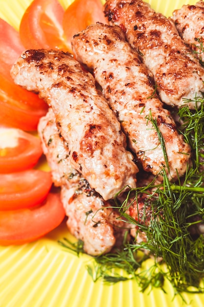 Brocheta de carne picada con eneldo verde y tomates en un plae