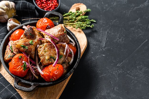 Brocheta de cerdo con tomate y pimiento en una sartén.