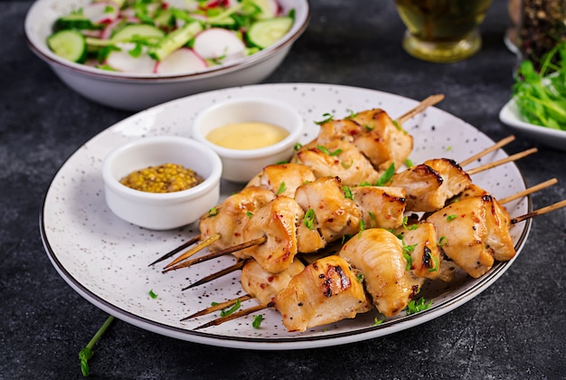 Brocheta de pollo a la parrilla y ensalada con pepino, rábano, cebolla