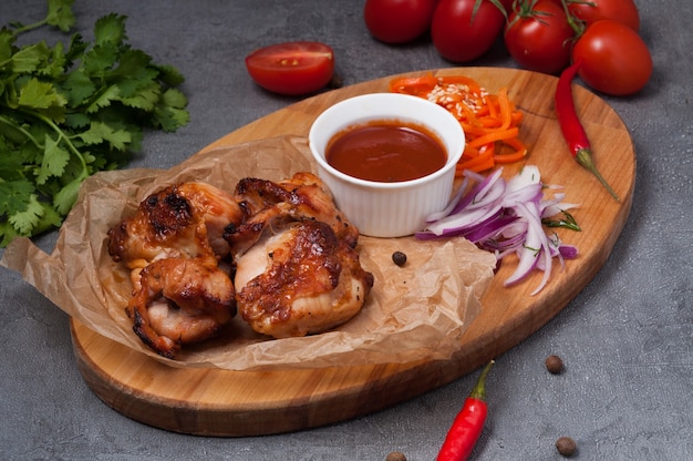 Brocheta de pollo con salsa de tomate sobre una tabla de madera