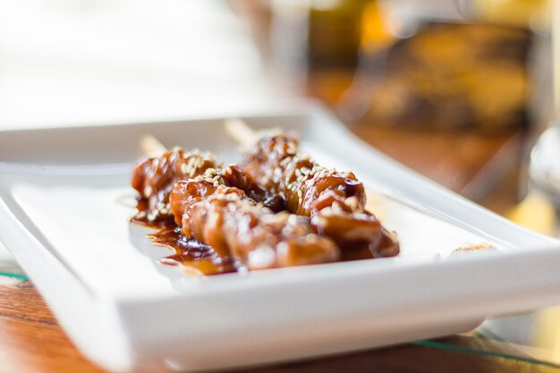 Brocheta de pollo teriyaki comida japonesa con semillas de sésamo en un plato rectangular