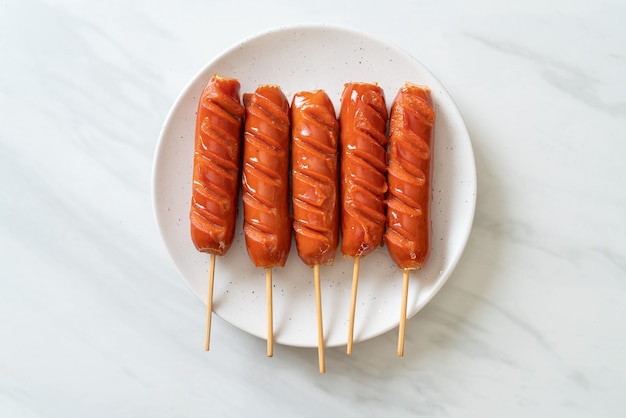 Brocheta de salchicha frita en la placa blanca.