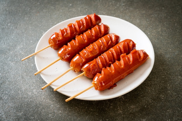 Brocheta de salchicha frita en la placa blanca.