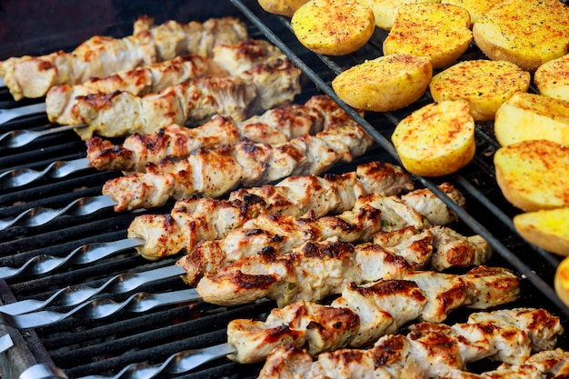 Brochetas de barbacoa con patatas y carne, así como brochetas, se asan en la parrilla.