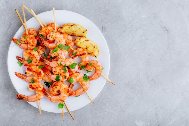 Brochetas de camarones al limón a la parrilla en un plato sobre fondo de piedra gris Vista superior con espacio para copiar