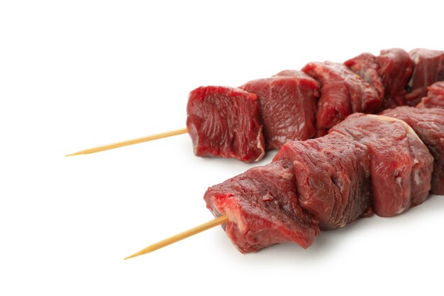 Brochetas con carne cruda aislado en blanco