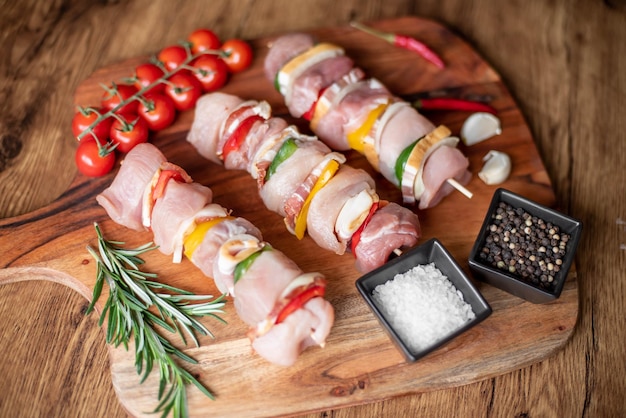 Brochetas de carne cruda con verduras sobre fondo de madera