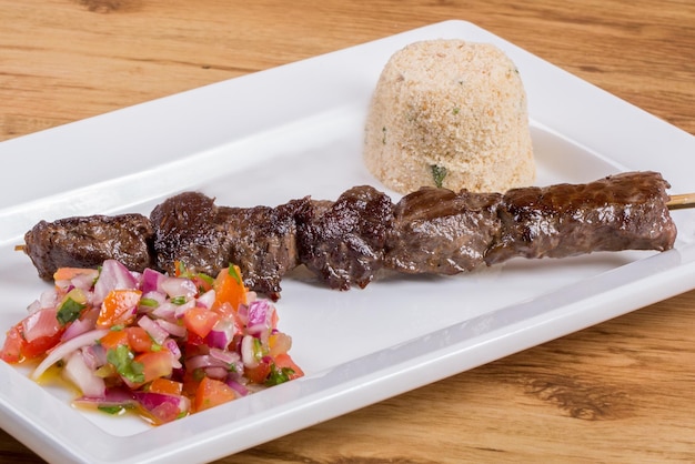 Brochetas de carne en mesa de madera