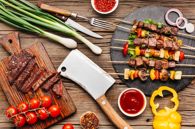 Brochetas de carne a la parrilla y bistec con vegetales en el escritorio de madera