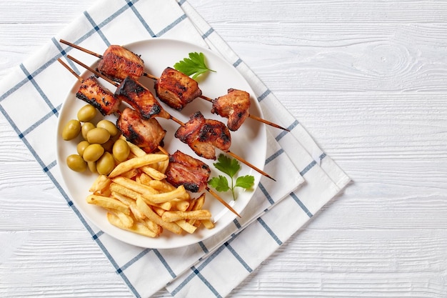 Brochetas de cerdo a la parrilla con papas fritas en un plato