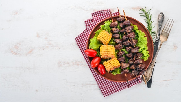 Brochetas de corazones de pollo, maíz y verduras frescas Sobre un fondo de madera Vista superior Espacio de copia libre