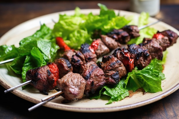 Brochetas de cordero sobre cama de verduras de hojas verdes