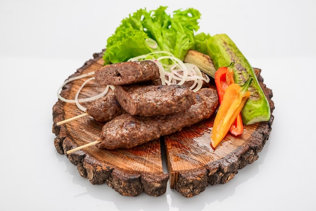 Brochetas de cordero en tabla para servir con verduras. Vista desde arriba, foto de estudio superior