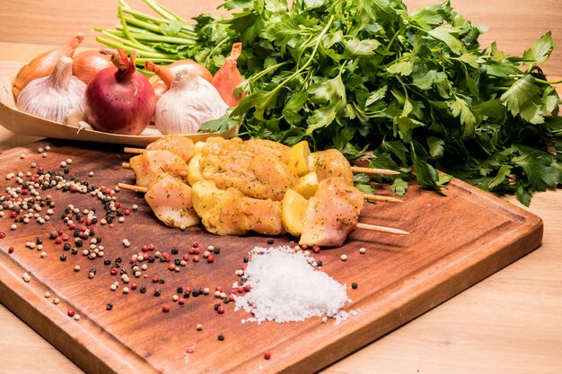 Foto brochetas de pollo crudo marinado con limón sobre una tabla de madera