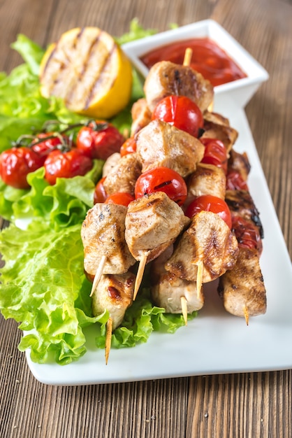 Brochetas de pollo a la parrilla en el plato blanco