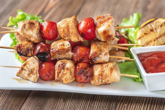 Brochetas de pollo a la parrilla en el plato blanco