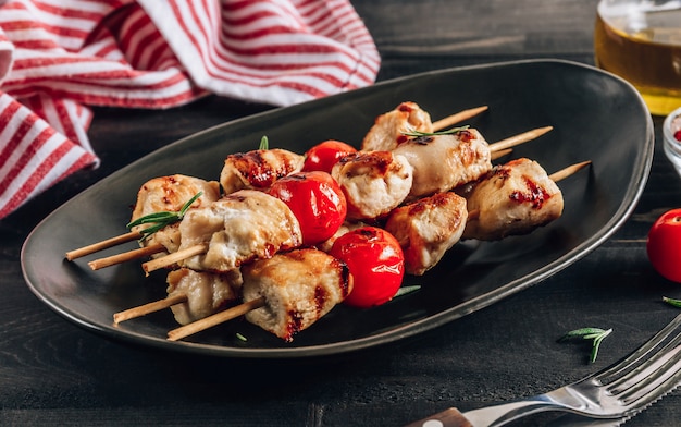 Brochetas de pollo a la plancha con tomates cherry en un plato