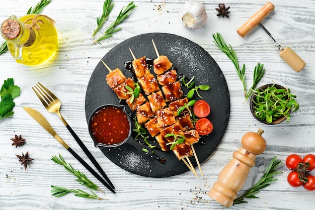 Brochetas de pollo con salsa teriyaki en un plato de piedra negra Menú de barbacoa de estilo rústico