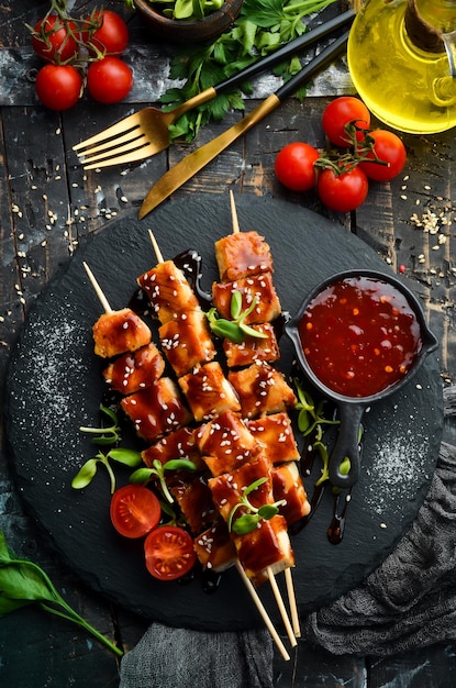 Brochetas de pollo con salsa teriyaki en un plato de piedra negra Menú de barbacoa de estilo rústico