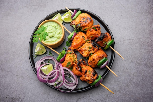 Brochetas de pollo tikka de la India, marinadas en especias y yogur y asadas en tandoor. servido con chutney verde y cebolla. enfoque selectivo